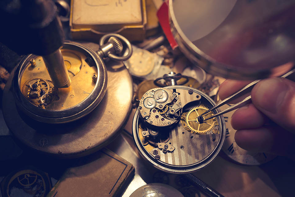 Un horloger place un rouage dans une montre ancienne